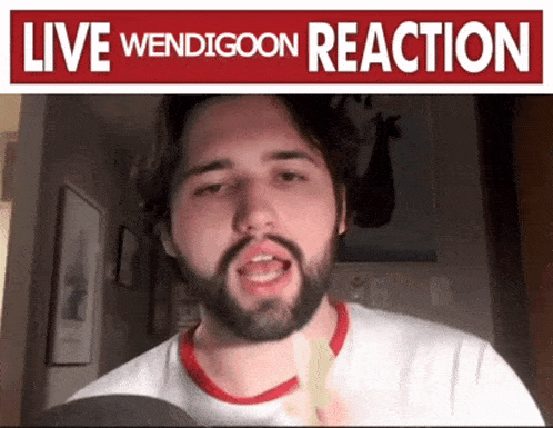 a man with a beard is holding a piece of paper in front of a sign that says live wendigoon reaction