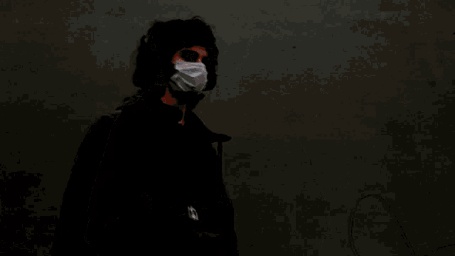 a person wearing a white face mask with a black background