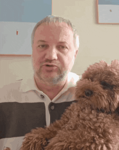 a man in a striped shirt is holding a brown dog
