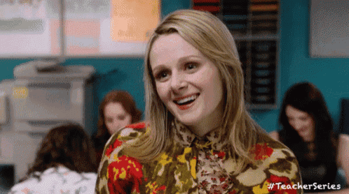 a woman is smiling in a classroom with other women .