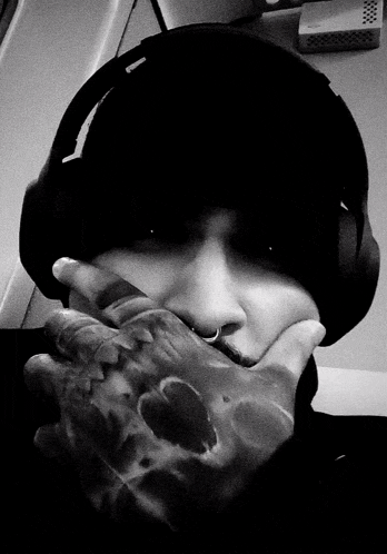 a person wearing headphones and covering their face with their hand