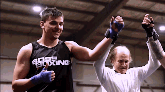 a man wearing a boss boxing tank top holds up his hand