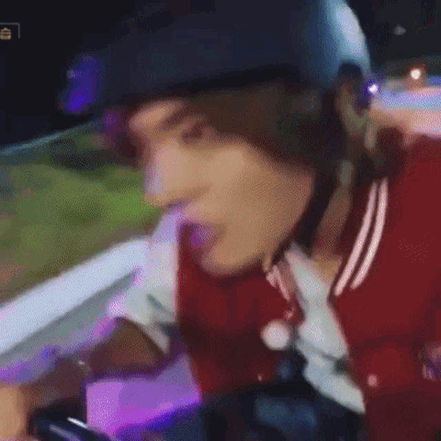 a man wearing a helmet and a red jacket is riding a scooter .