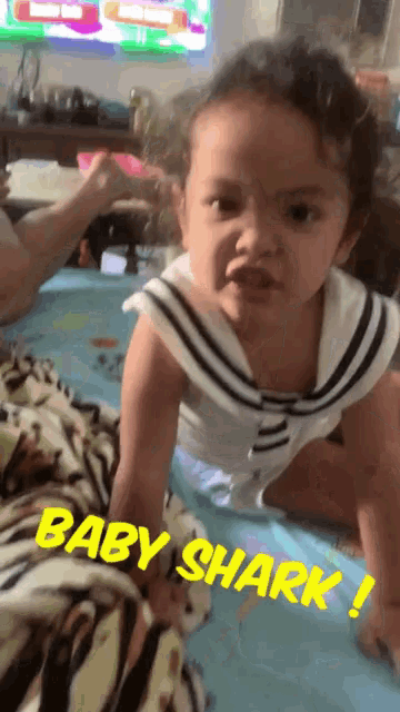 a little girl is crawling on a bed and the words baby shark are on the bottom