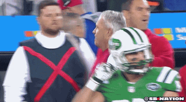 a new york jets football player is being escorted by a security guard