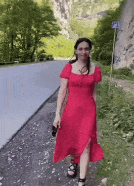 a woman in a red dress is walking down a road next to a sign that says 20