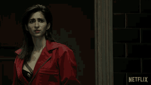 a woman in a red jacket is standing in front of a wall that says netflix
