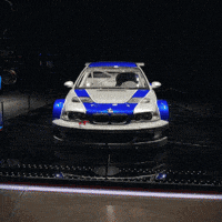 a blue and silver sports car with a reflection of the car in the water