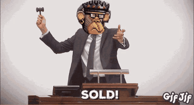 a man in a suit and tie is holding a hammer in front of a podium that says sold