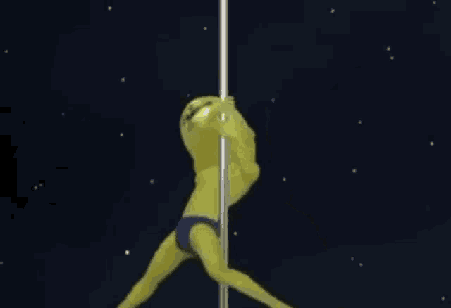 a yellow alien is dancing on a pole in the space .
