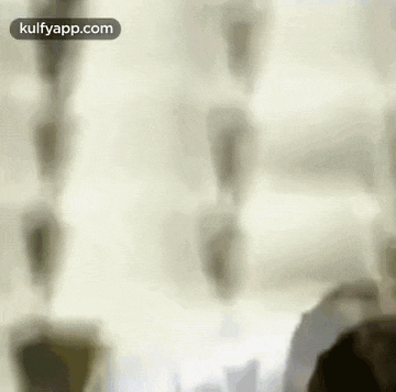 a blurry picture of a person standing in front of a window with a white curtain .