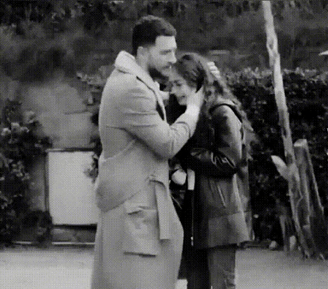 a black and white photo of a man touching a woman 's face