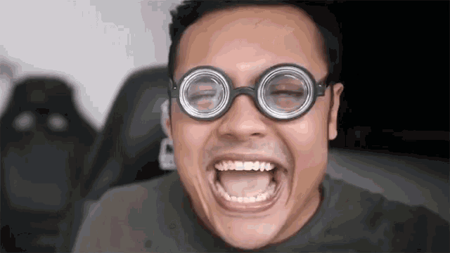 a man wearing glasses is making a funny face with his mouth wide open .