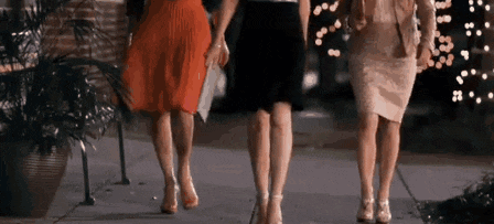 a group of women are walking down a sidewalk .