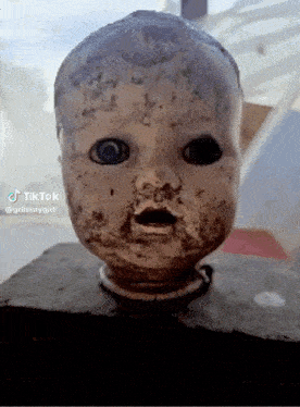 a close up of a doll 's head on a block .