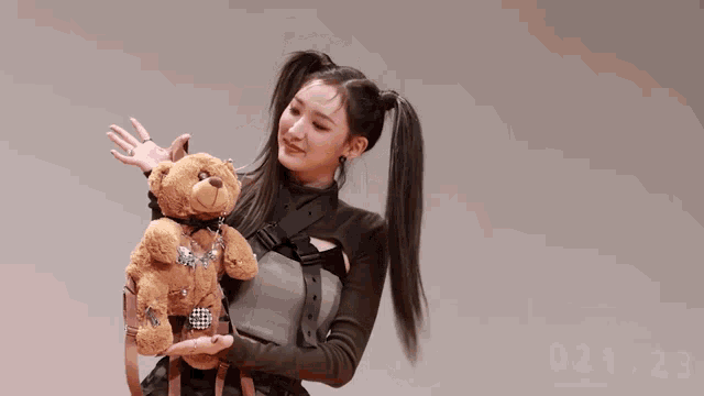 a woman with pigtails is holding a teddy bear with a backpack on it