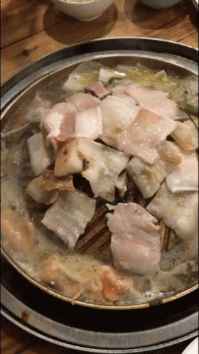 a pan filled with meat and vegetables is sitting on a wooden table