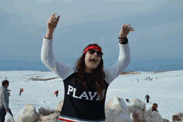a woman wearing a sweater that says play is standing in the snow