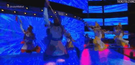 a group of people are dancing on a stage in front of a large screen .