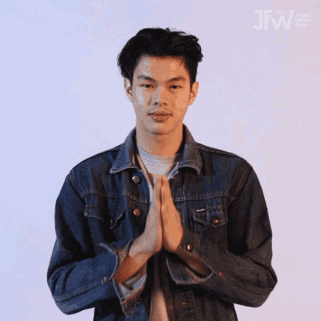 a man in a denim jacket is praying with the words jfw visible in the corner