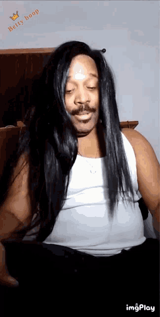 a man with long black hair and a mustache is wearing a white tank top and a wig