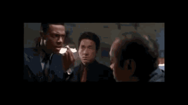 a man in a suit talks to two other men