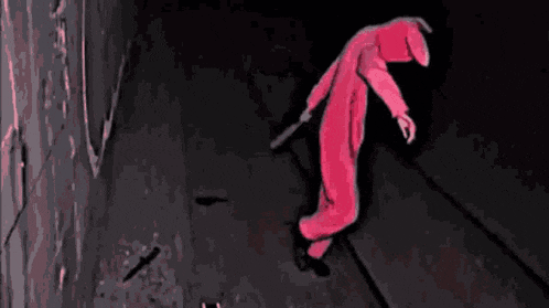 a person in a pink jumpsuit is holding a knife in their hand .