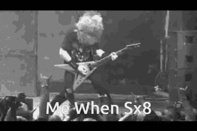 a black and white photo of a man playing a guitar on a stage in front of a crowd .