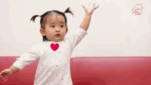 a little girl in a white shirt with a red heart on it