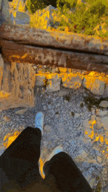 a person walking on a rocky path with a wooden railing behind them