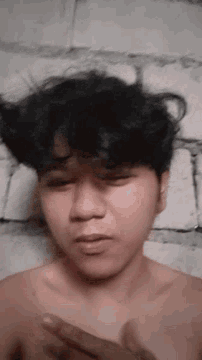 a man without a shirt is laying on the floor with his eyes closed and his hands on his chest .
