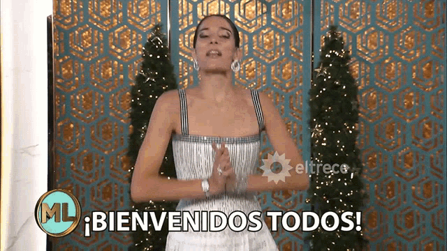 a woman in a white dress is standing in front of a sign that says ml bienvenidos todos