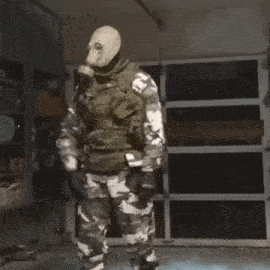 a man in a military uniform with a backpack on his back is squatting down .