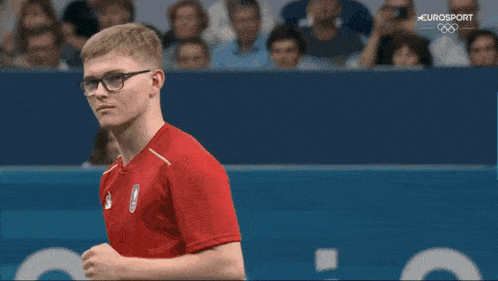 a young man wearing glasses and a red shirt with the number 1 on the back