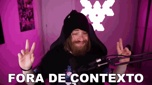 a man giving a peace sign in front of a microphone with the words fora de contexto above him