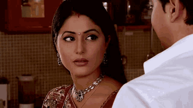 a woman with a red bindi on her forehead looks at a man