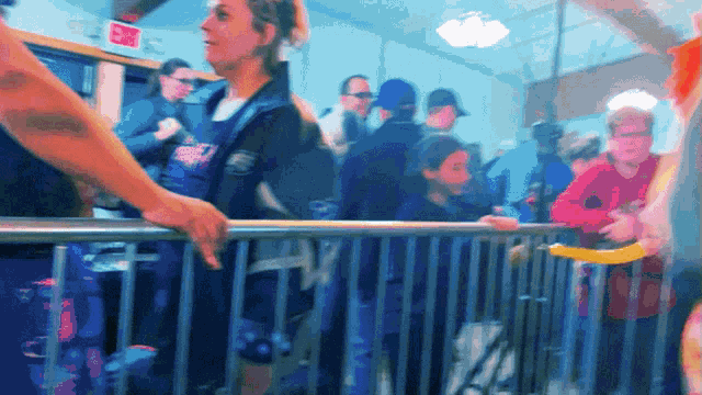 a group of people standing behind a fence with a red exit sign in the background