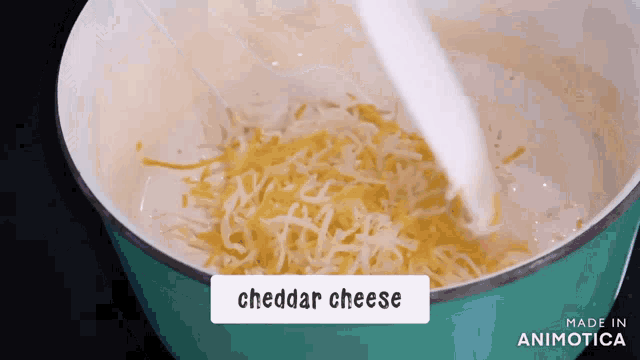 cheddar cheese is being added to a sauce in a pot