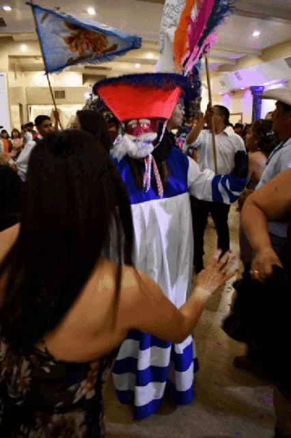 a woman in a blue and white striped dress is dancing with a man in a clown costume