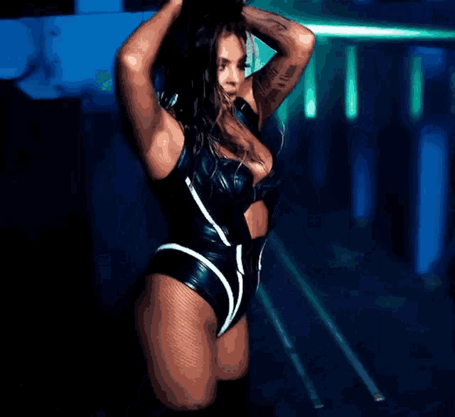 a woman in a very tight bodysuit is standing in a dark room .