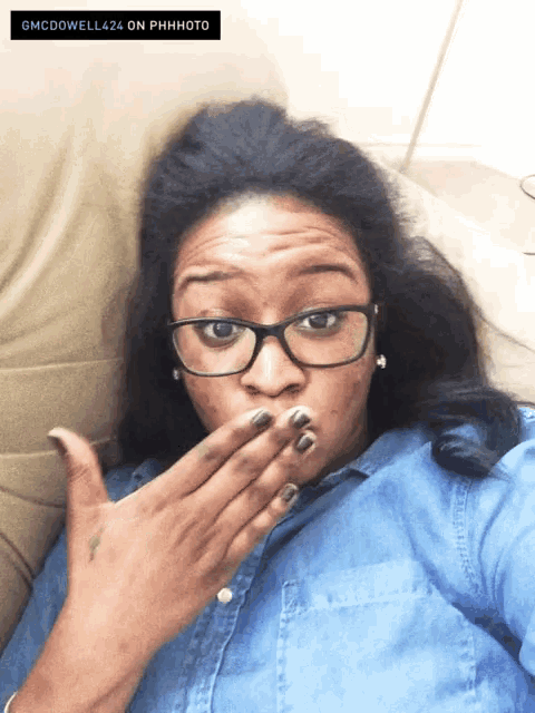 a woman wearing glasses covering her mouth with her hand and the words gmcdowell424 on phhphoto above her