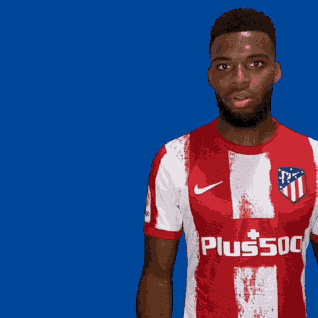 a man with a beard wears a red and white shirt that says plus500