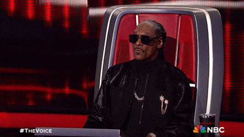 a man wearing sunglasses is sitting in a chair with the nbc logo on the bottom