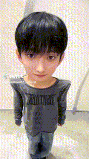 a young boy is wearing a gray shirt and jeans and has a big head .