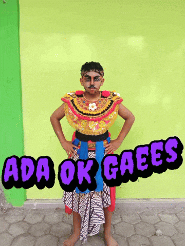 a boy in a colorful costume stands in front of a green wall with the words ada ok gaees