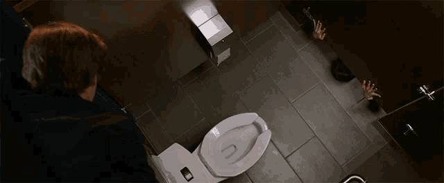 a person in a bathroom with their hands behind a stall