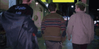 a group of people walking down a street at night .