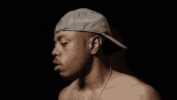 a shirtless man wearing a hat and a necklace is looking down .