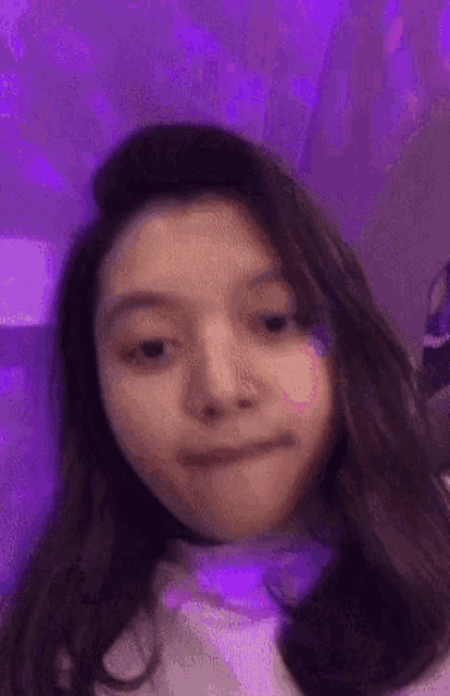a young woman is making a funny face in front of a purple light .