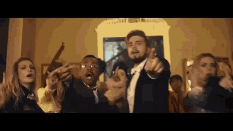 a group of people are standing in a room holding guns and pointing at each other .